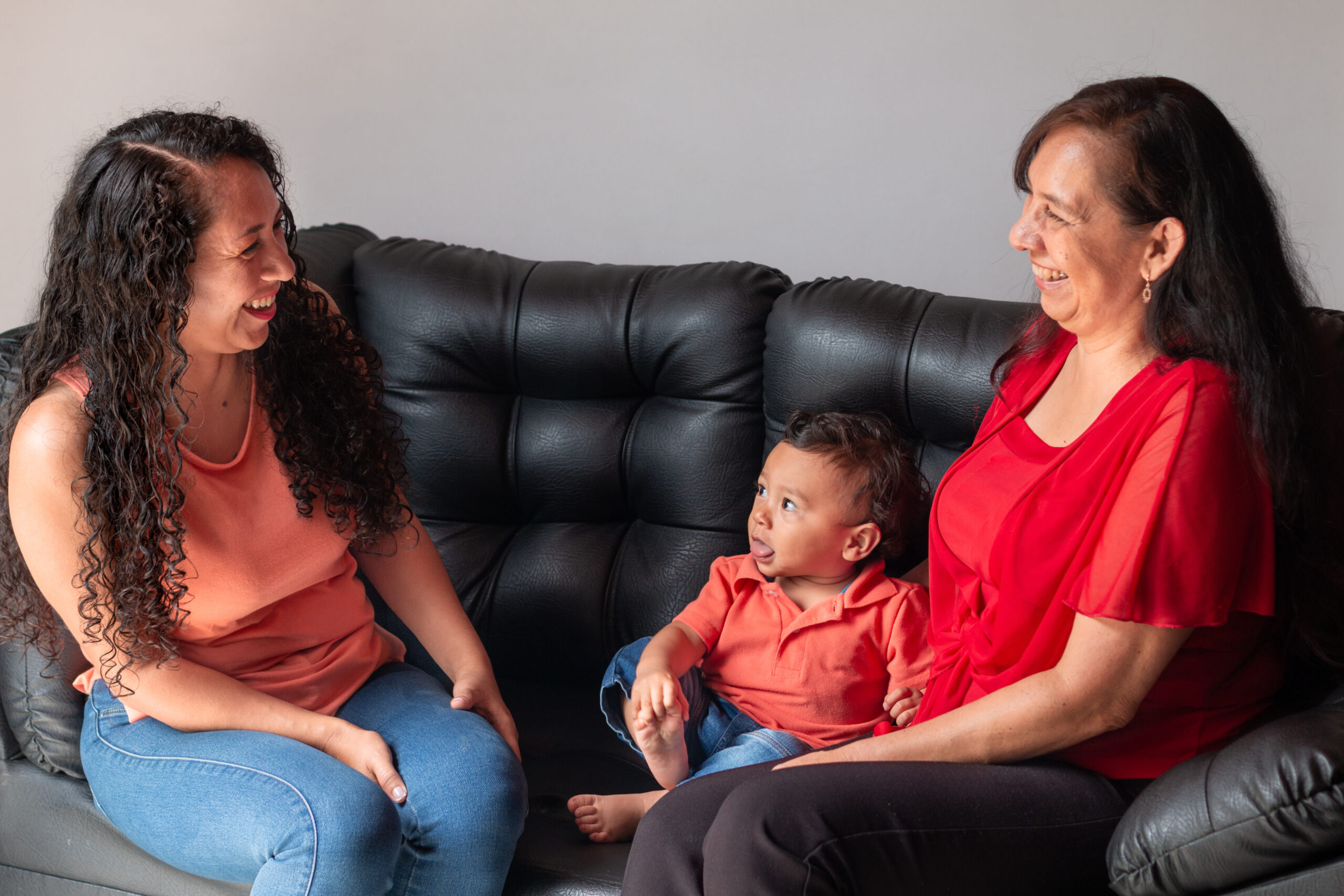 Daughter and grandson socializing with grandma. Mom and daughter laughing together on the couch at home.